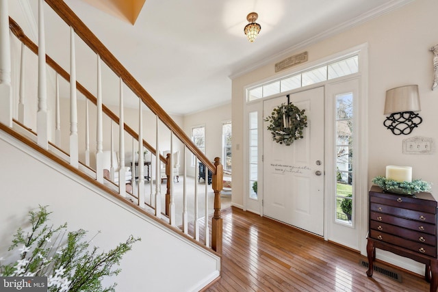 entryway with crown molding, stairway, and hardwood / wood-style floors