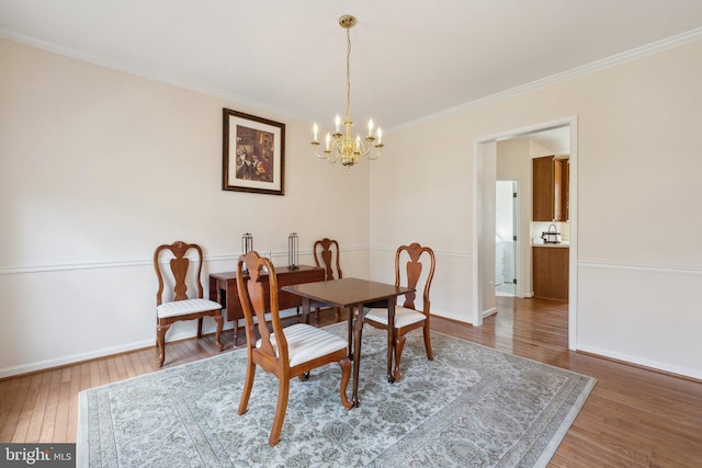 dining space with a chandelier, crown molding, baseboards, and wood finished floors