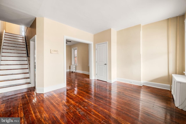 empty room with dark wood-style flooring, stairway, and baseboards