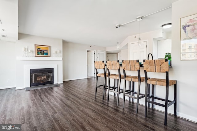 kitchen with dark wood-style flooring, a glass covered fireplace, and baseboards