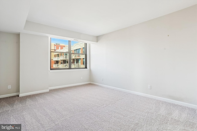 spare room featuring carpet and baseboards