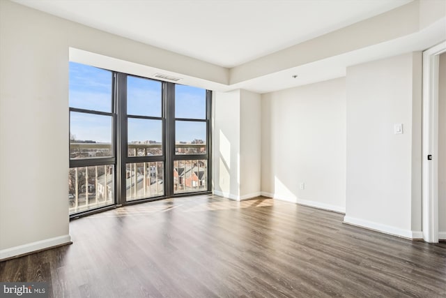 spare room featuring visible vents, a view of city, baseboards, and wood finished floors