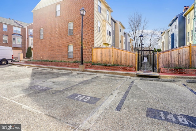 exterior space featuring a residential view, uncovered parking, fence, and brick siding