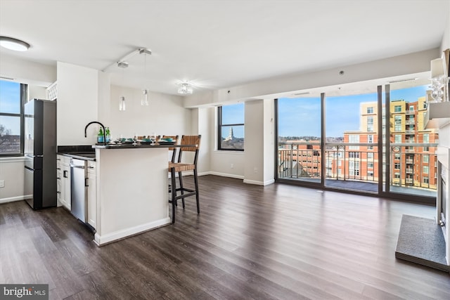 kitchen featuring dark wood-style flooring, dark countertops, appliances with stainless steel finishes, white cabinetry, and a sink