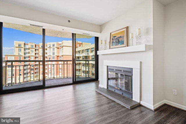 unfurnished living room with baseboards, wood finished floors, and a glass covered fireplace