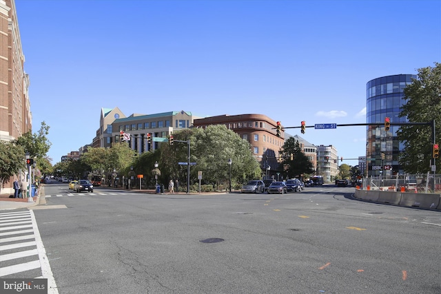 view of street featuring traffic lights, curbs, traffic signs, sidewalks, and street lights