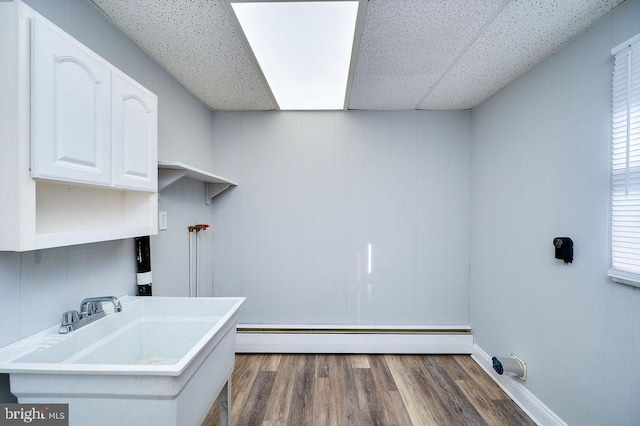 laundry area featuring laundry area, dark wood-style floors, a baseboard heating unit, and a sink