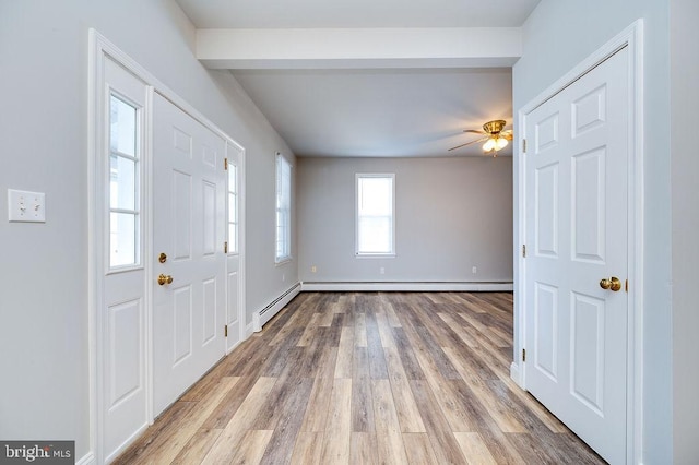 entryway with ceiling fan, light wood finished floors, baseboard heating, and baseboards