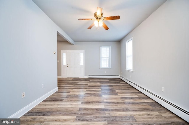 spare room with ceiling fan, baseboards, baseboard heating, and wood finished floors