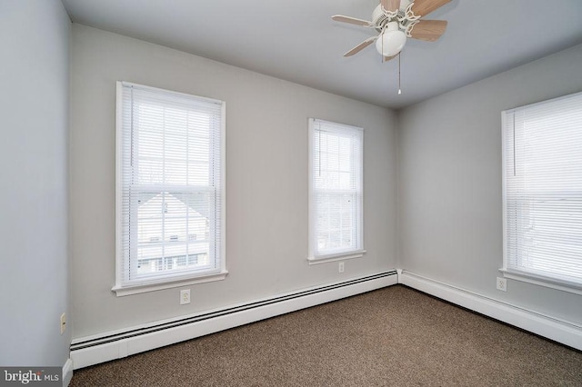 carpeted spare room featuring a baseboard heating unit, ceiling fan, and a healthy amount of sunlight