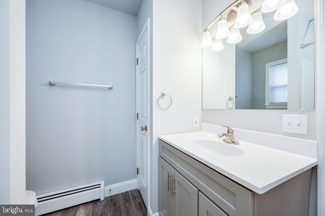 bathroom with a baseboard radiator, toilet, wood finished floors, vanity, and baseboards