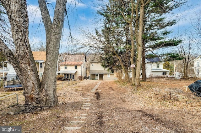 view of front of house featuring dirt driveway and a trampoline