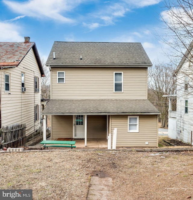 back of property with a shingled roof and a patio