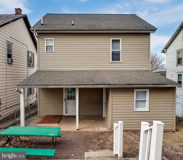 back of house with a shingled roof and a patio area