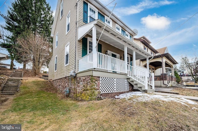 exterior space with covered porch, a front lawn, and stairway