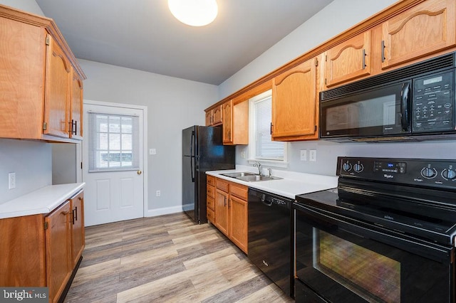 kitchen with black appliances, light wood-style flooring, plenty of natural light, and a sink