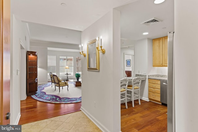 corridor with visible vents, baseboards, and light wood finished floors