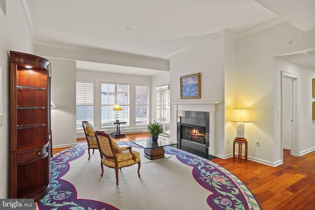 living area featuring a fireplace with flush hearth, ornamental molding, baseboards, and wood finished floors