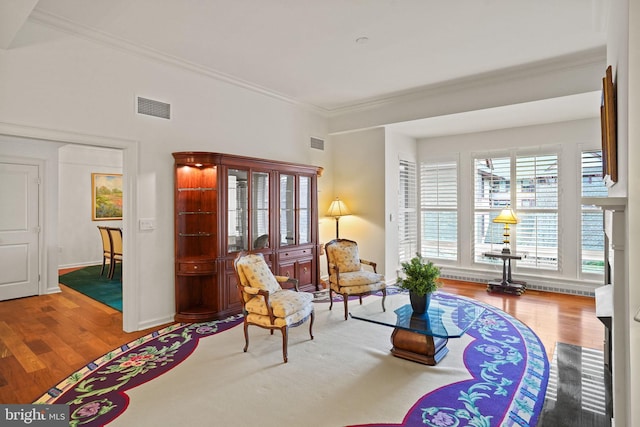 living area with wood finished floors, visible vents, and ornamental molding