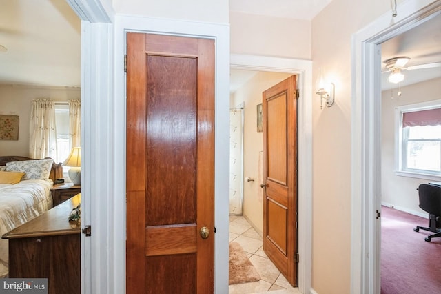 hall with light tile patterned floors and light carpet