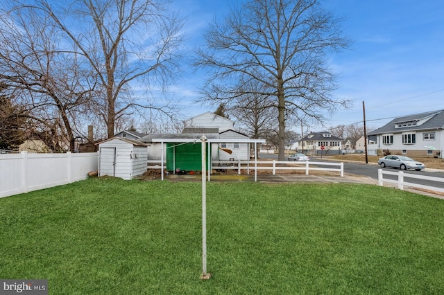 view of yard with a residential view, an outbuilding, a shed, and fence