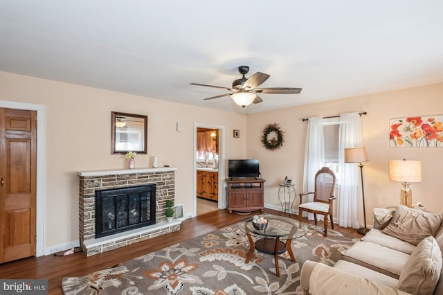 living area with ceiling fan, baseboards, wood finished floors, and a fireplace