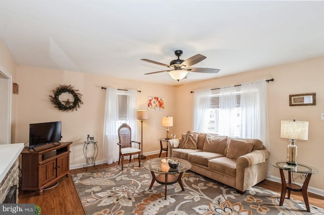 living area featuring baseboards, ceiling fan, and wood finished floors