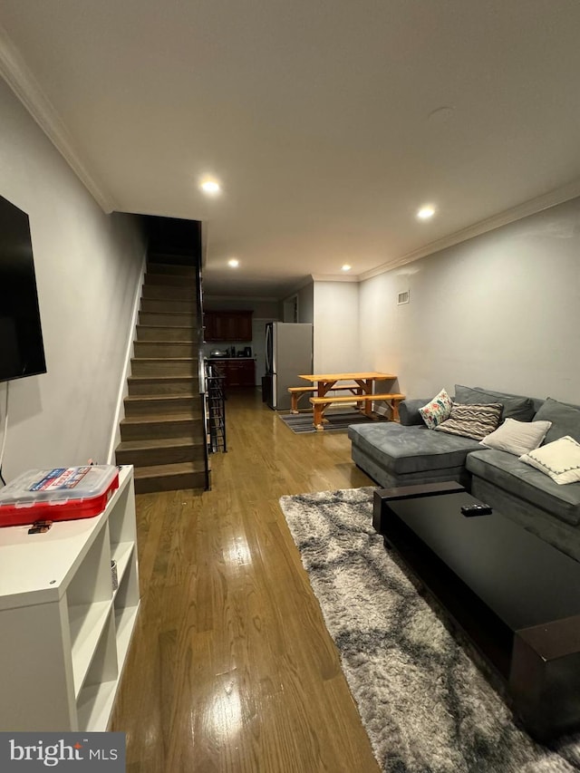 living area with ornamental molding, stairway, wood finished floors, and recessed lighting