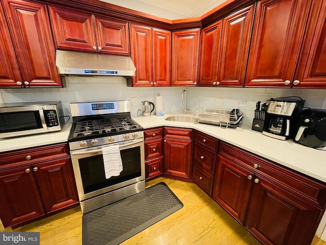 kitchen with light countertops, appliances with stainless steel finishes, extractor fan, and a sink