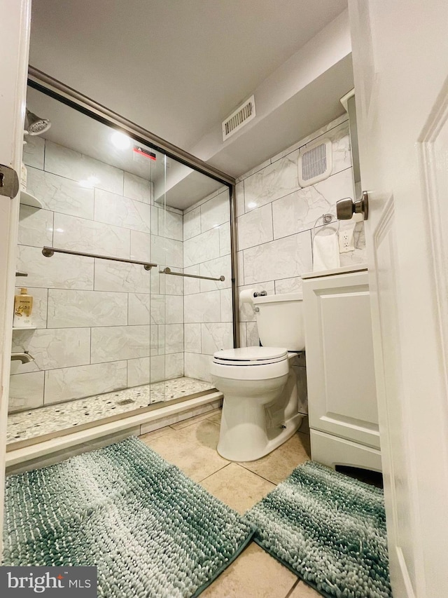 bathroom featuring tile walls, visible vents, toilet, a stall shower, and tile patterned floors