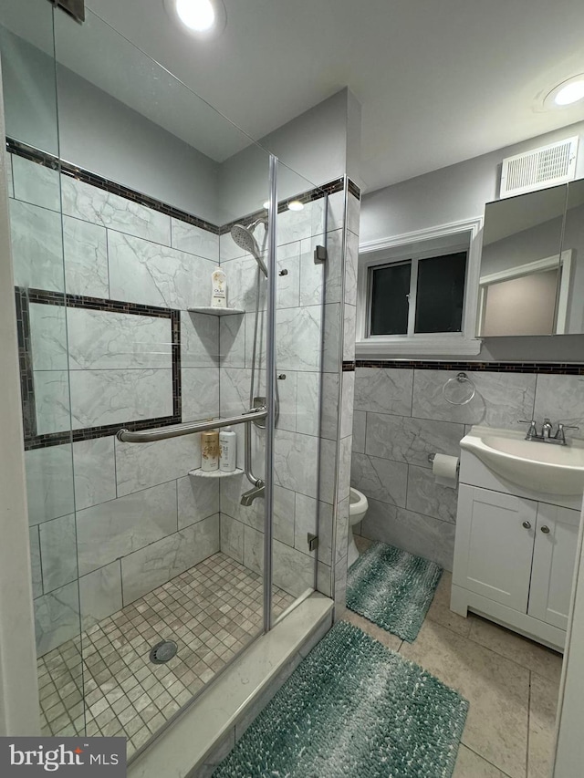 full bath featuring tile walls, a shower stall, toilet, and vanity