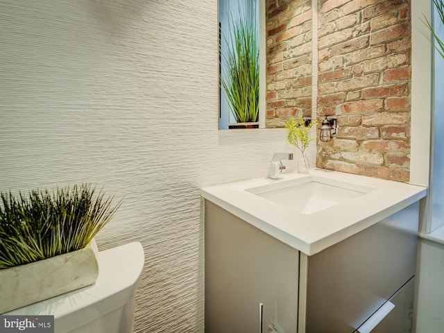 bathroom featuring vanity and brick wall