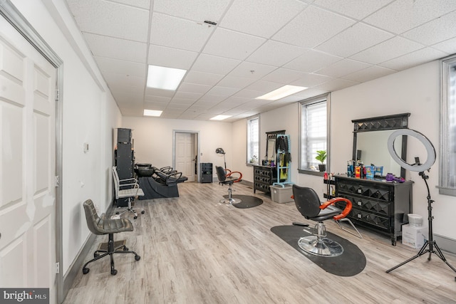 exercise room with a drop ceiling, light wood-type flooring, and baseboards