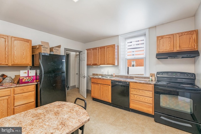 kitchen featuring black appliances, under cabinet range hood, light stone counters, and a sink