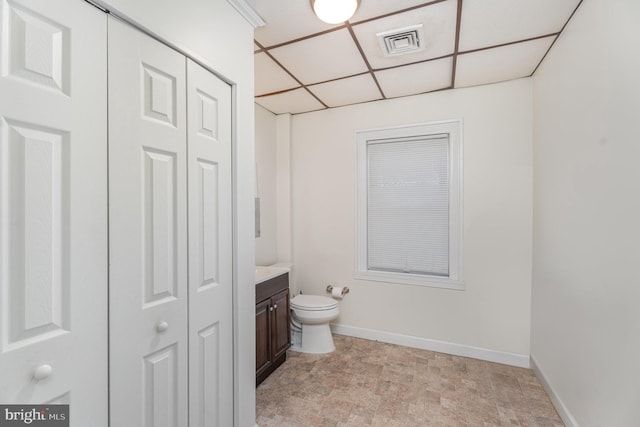 half bathroom with a closet, visible vents, toilet, vanity, and baseboards