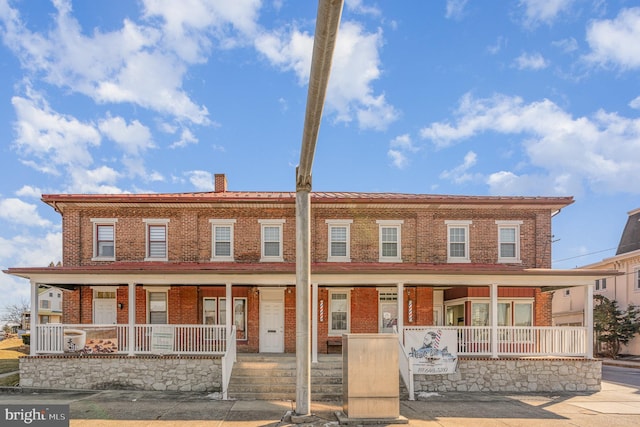 townhome / multi-family property featuring covered porch, brick siding, and a chimney