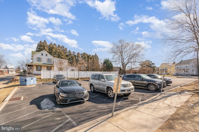 uncovered parking lot featuring a residential view and fence