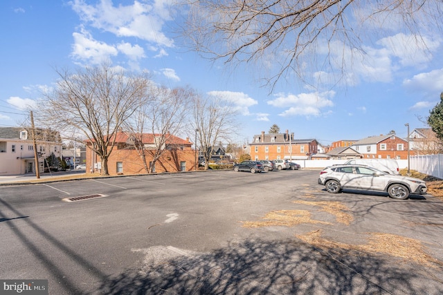 uncovered parking lot featuring a residential view and fence