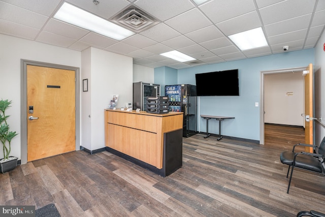 office area featuring dark wood-type flooring, a drop ceiling, visible vents, and baseboards