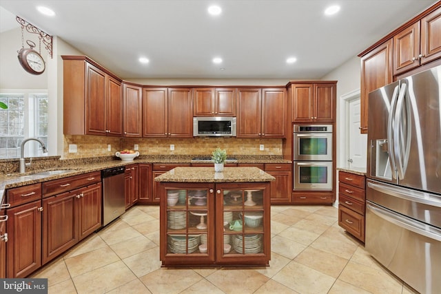 kitchen featuring stainless steel appliances, light stone countertops, a sink, and tasteful backsplash