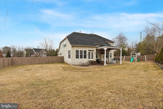 rear view of property featuring entry steps, a lawn, a fenced backyard, a patio area, and a playground