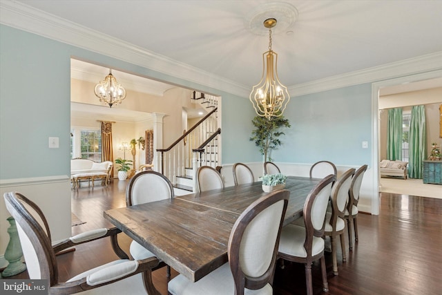 dining area featuring ornate columns, a notable chandelier, hardwood / wood-style floors, and stairs