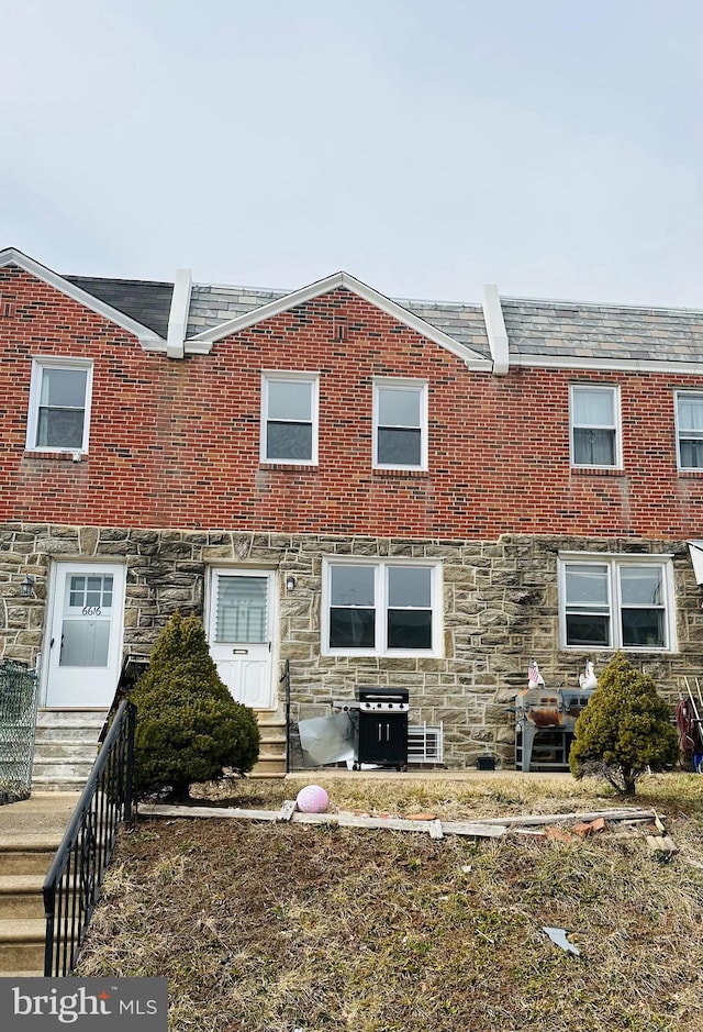 townhome / multi-family property featuring entry steps, stone siding, and brick siding