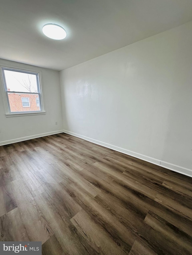 spare room featuring dark wood-style floors and baseboards