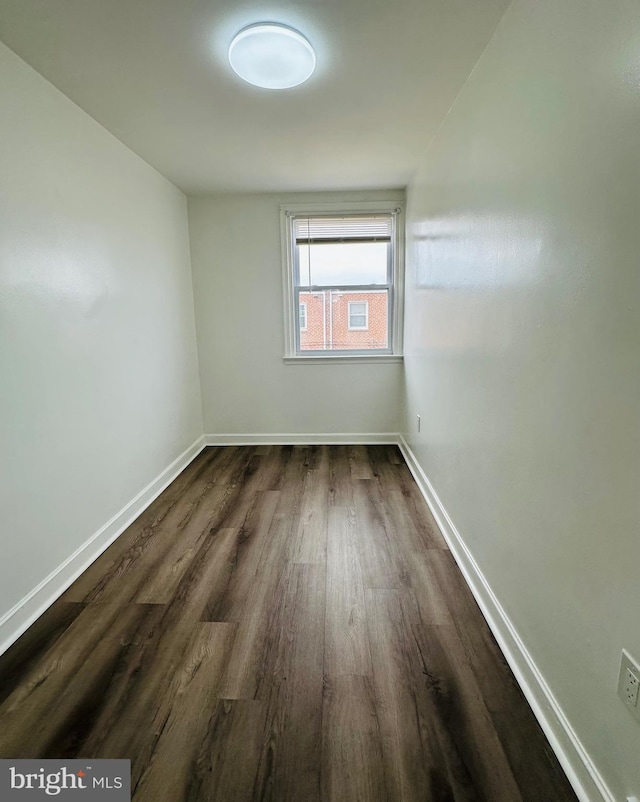 unfurnished room featuring dark wood-style flooring and baseboards