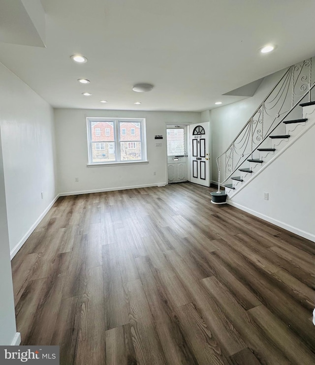 unfurnished living room featuring stairs, recessed lighting, dark wood-style floors, and baseboards