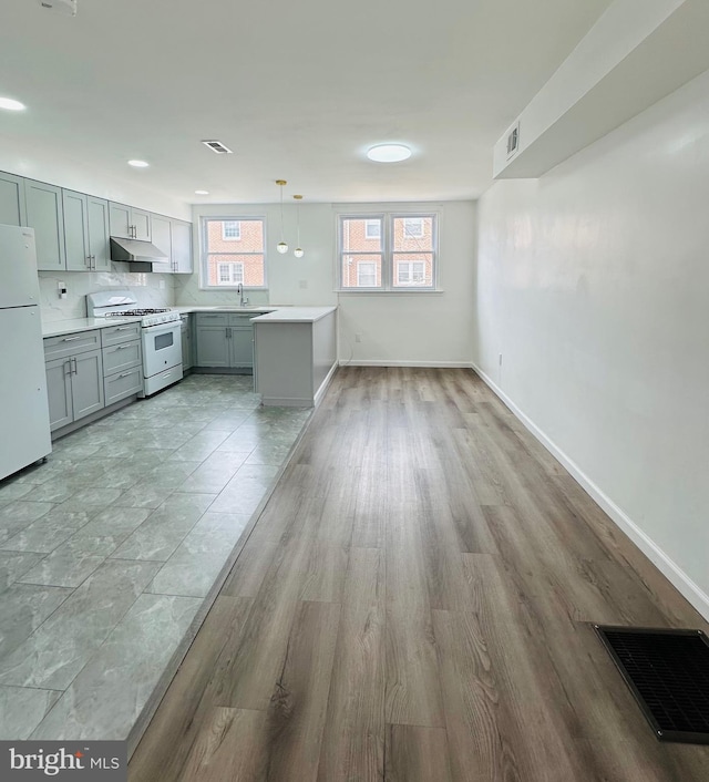 kitchen featuring light countertops, hanging light fixtures, visible vents, white appliances, and under cabinet range hood