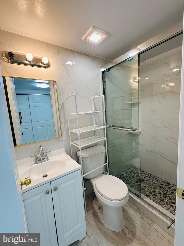 full bath featuring toilet, vanity, and a marble finish shower