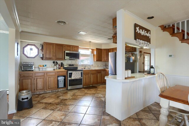 kitchen with visible vents, wainscoting, a peninsula, stainless steel appliances, and light countertops