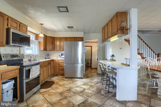 kitchen with hanging light fixtures, backsplash, appliances with stainless steel finishes, a sink, and a kitchen breakfast bar